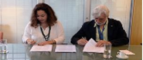 Uma mulher e um homem, sentados um ao lado do outro, assinam papéis. 